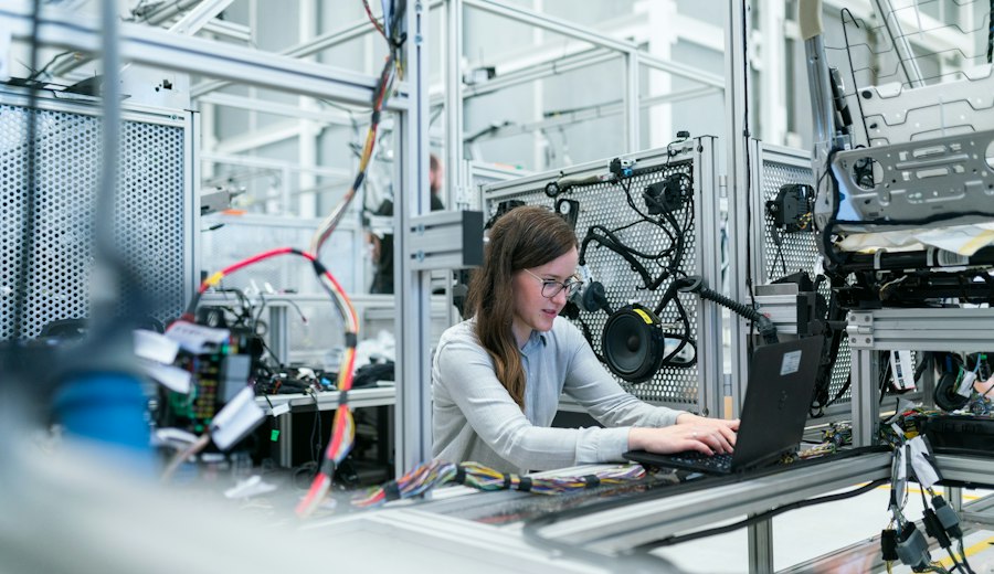 An engineer working at a laptop beside production equipment