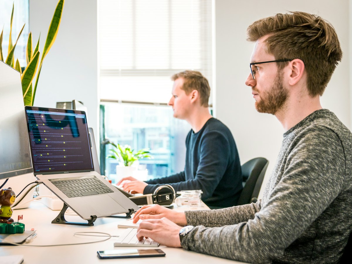 Two developers working side by side at their desks